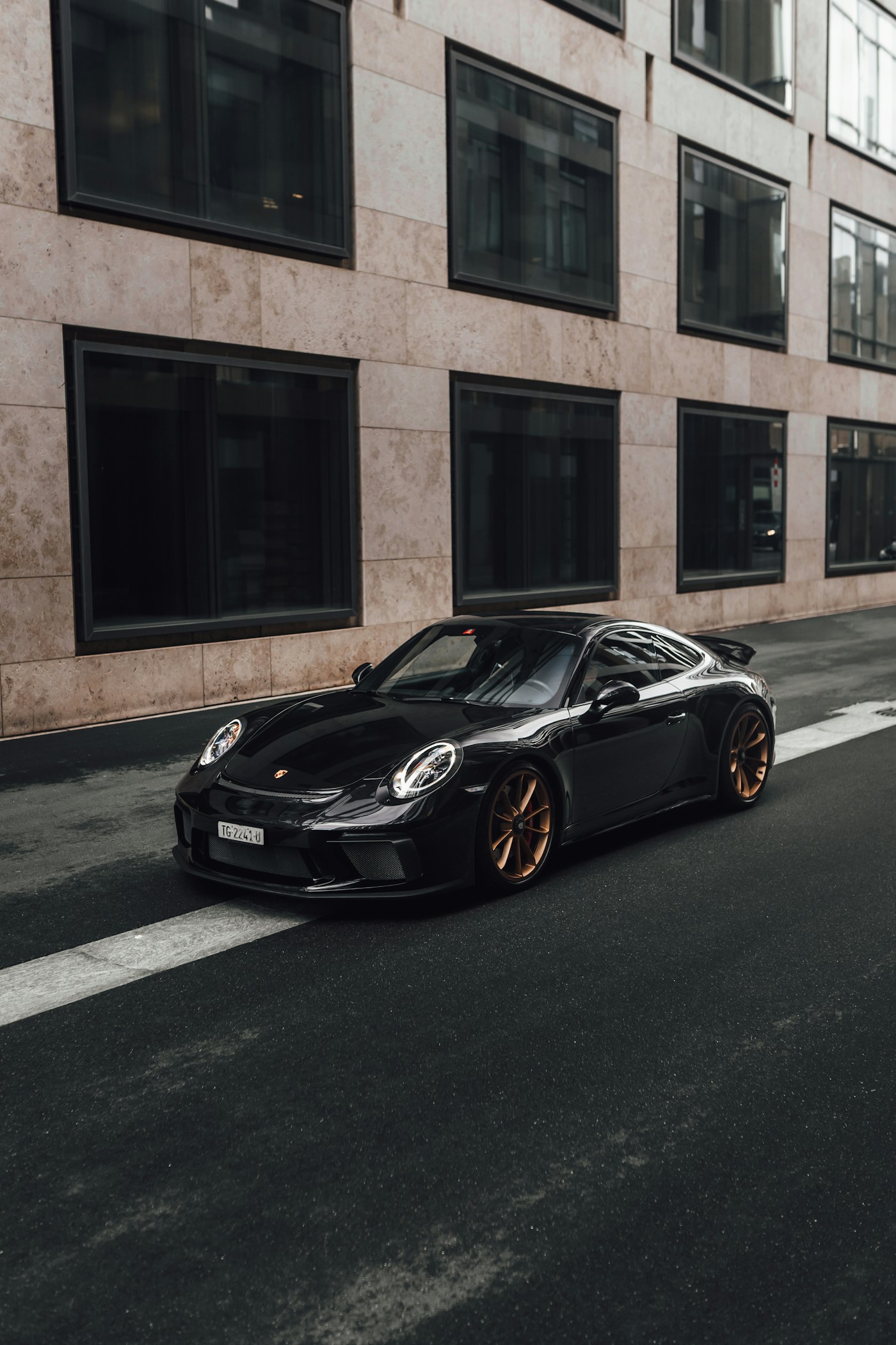 Black Porsche 911 parked beside an urban building